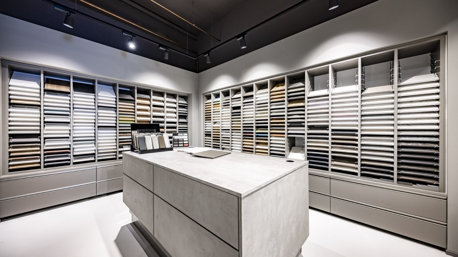 Musterstudio für Materialauswahl mit zahlreichen Küchenfronten und Arbeitsplattenmustern – wichtiges Element für ein interaktives Ladenbaukonzept im Küchenstudio.