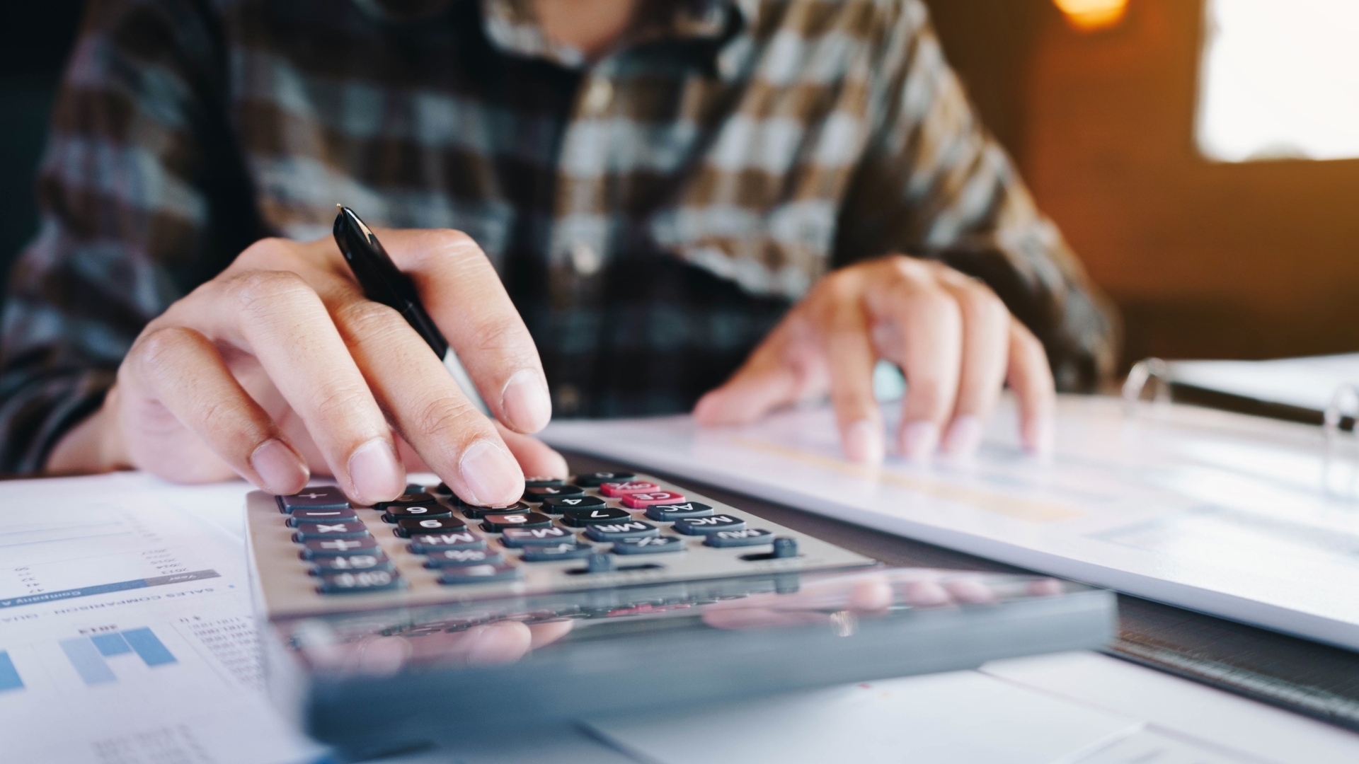 Existenzgründer kalkuliert Finanzplan mit Taschenrechner – KfW StartGeld erleichtert die Finanzierung der Küchenstudio-Gründung.