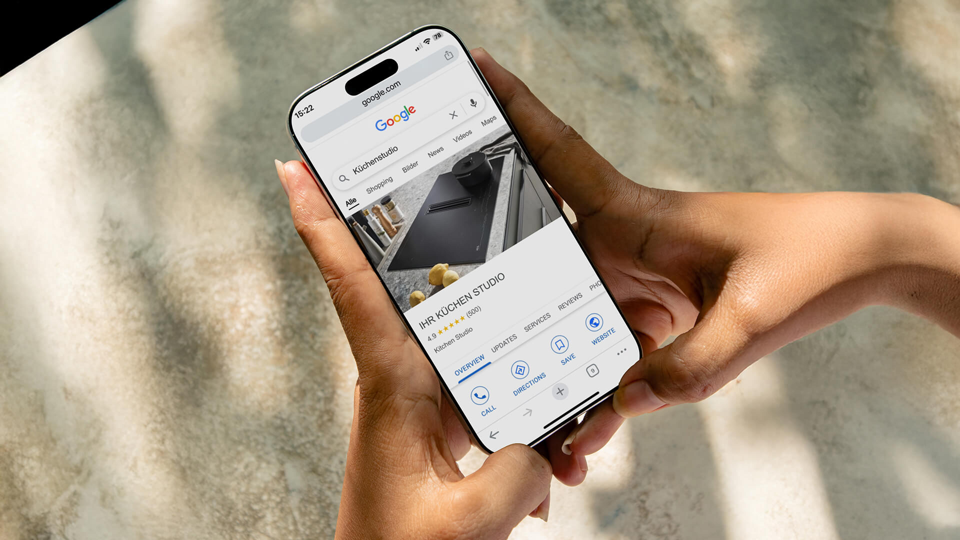 Person hält ein Smartphone mit einer Google-Suche nach „Küchenstudio“ – Beispiel für lokale Online-Sichtbarkeit über Google My Business.